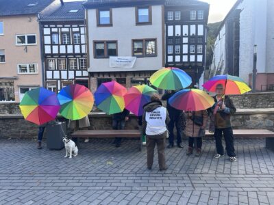 7 Menschen mit Regenbogen-Schirmen und 1 Oma gegen Rechts